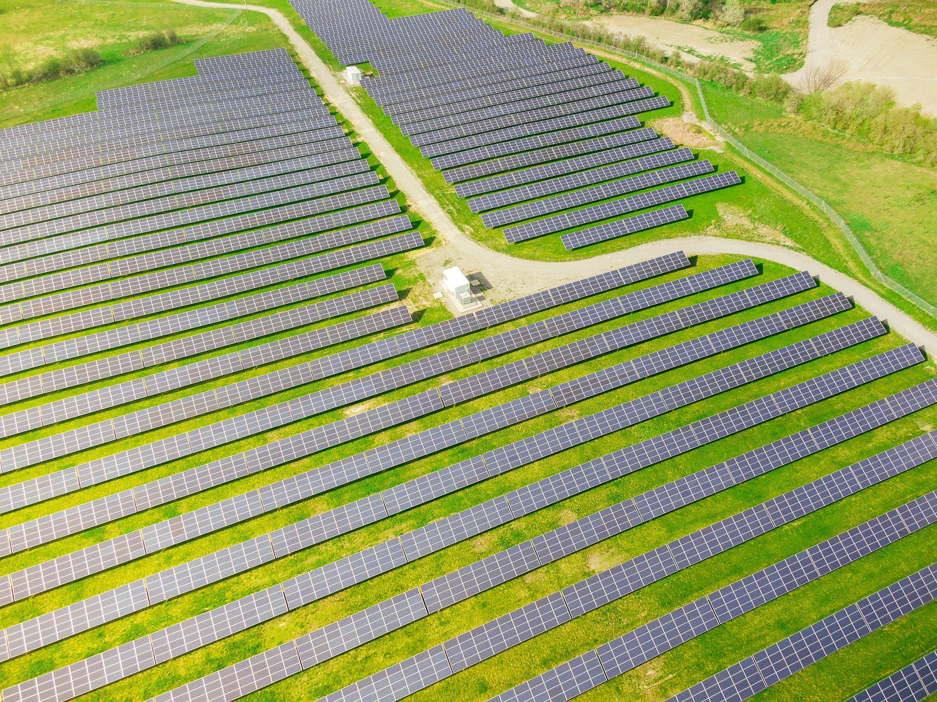 Alt=»Obligation de solarisation qui est concerné ? Panneaux solaires au sol sur un grand terrain.»