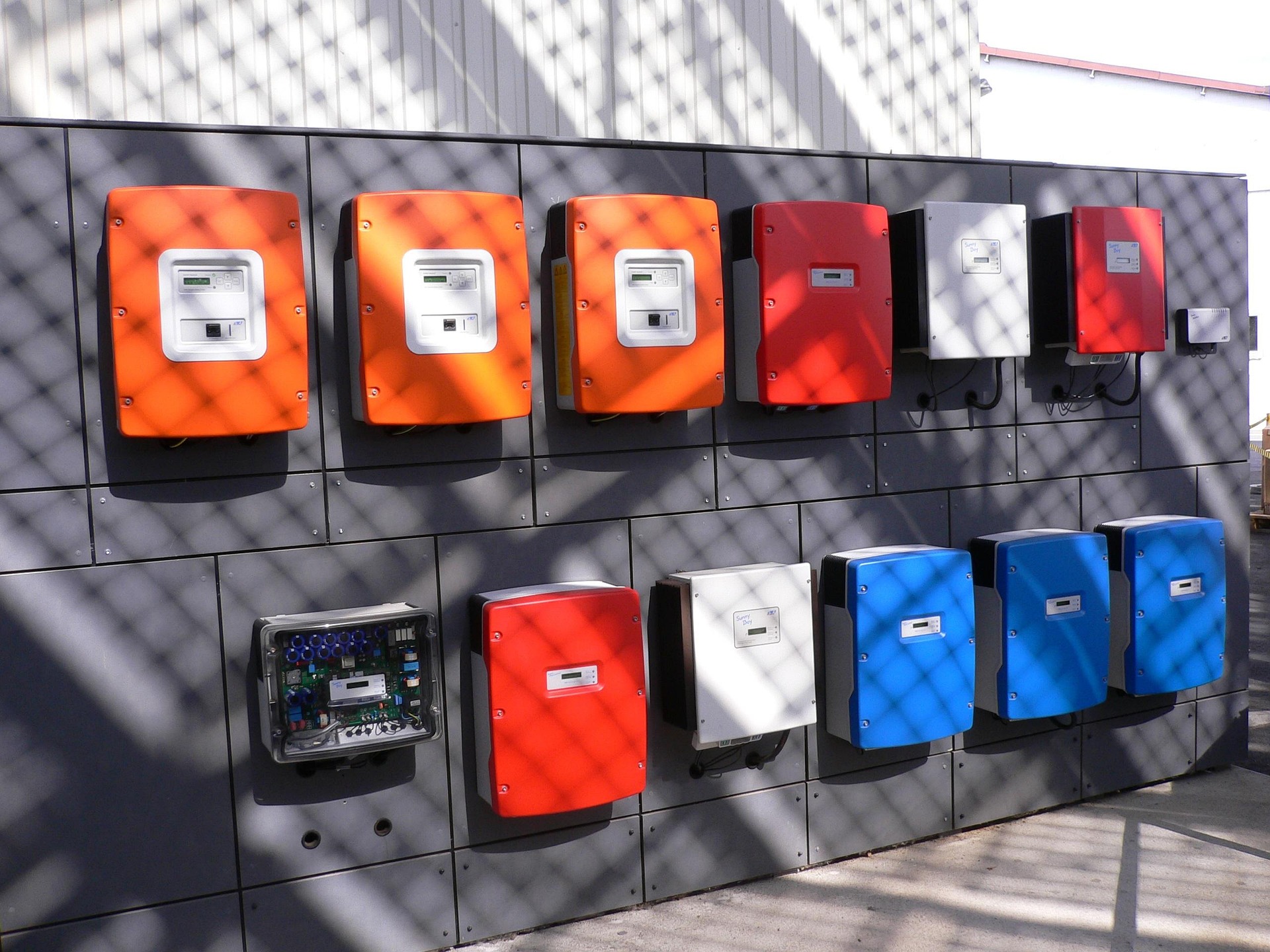 Alt=»Différence entre onduleur et micro-onduleur. Plusieurs onduleurs solaires sur un mur.»